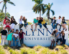 group of students sitting on the Lynn University sign