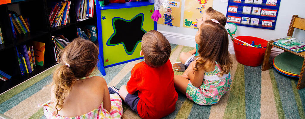 young children in a classroom looking at a toy
