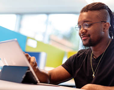 African American male student smiling and working on a tablet